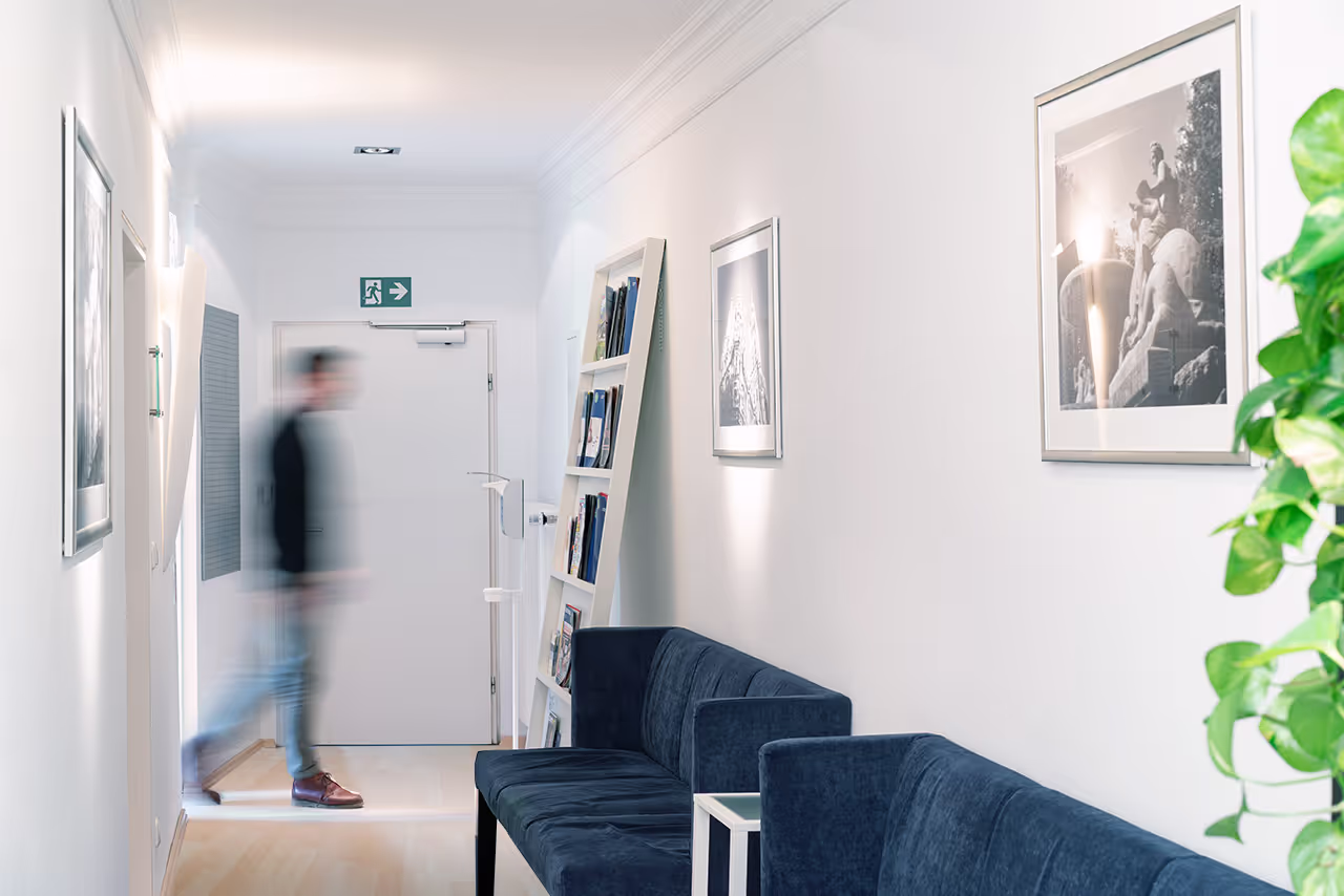 Flur und Eingangsbereich der Praxis, helle Beleuchtung und Sofas im Vordergrund